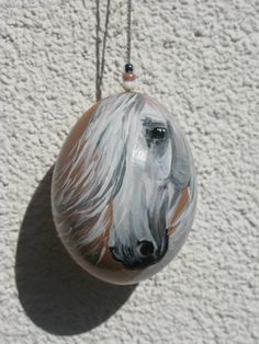 a glass ornament with a white horse painted on it's face hanging from a cord