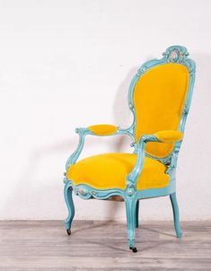 a blue and yellow chair sitting on top of a hard wood floor next to a white wall