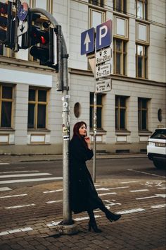 a woman leaning against a pole next to a traffic light