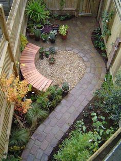 a small garden with lots of plants and rocks in the center, along with a wooden fence