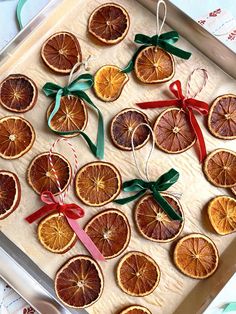 orange slices are arranged on a baking sheet with red ribbon and green bows, as well as twine ribbons