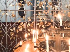 several candles are lit in front of a decorative iron gate with gold flowers on it