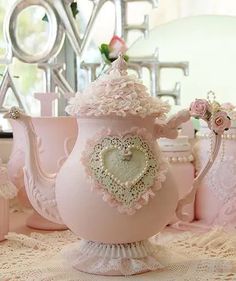 there is a pink tea pot with a heart on the top and flowers in the bottom