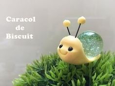 a close up of a small toy insect on some grass with the words caracol de biscuit above it