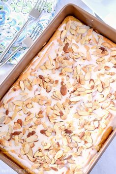 a baking dish with almonds and icing in it on a table next to utensils