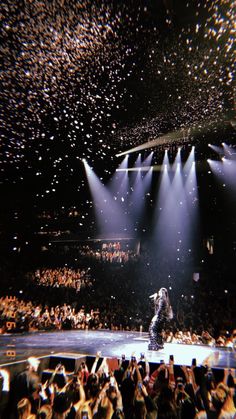 an audience is watching a man on stage in front of bright spotlights and confetti falling from the ceiling