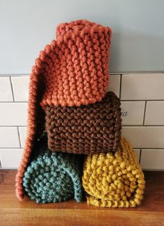 several knitted items stacked on top of each other in front of a tiled wall