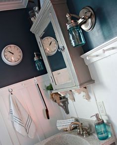 a bathroom with two clocks on the wall and a sink in front of an open cabinet