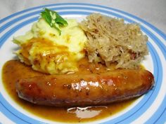 a plate with sausage, mashed potatoes and gravy