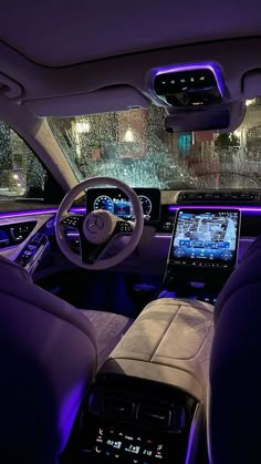 the interior of a car with purple lights and electronic devices on the dash board in front of it