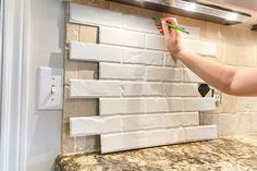 a woman is painting a brick wall with green paint and some white bricks on it