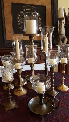 a table topped with lots of glass vases and candles