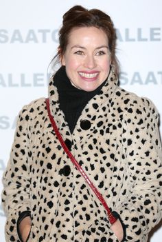 a woman in a spotted coat smiles at the camera