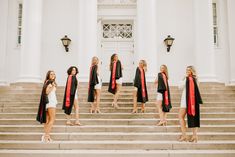 a group of women in graduation gowns standing on the steps of a white building