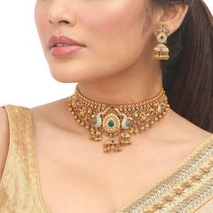 a woman wearing a gold necklace and earrings