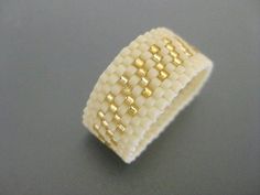 a white and gold woven ring on a gray surface