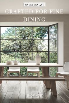 a table and chairs in front of a large window with the view of trees outside