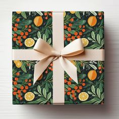 a wrapped gift box with oranges and leaves on it