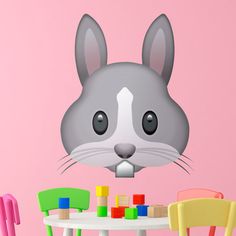 a gray and white chino face on a pink wall next to colorful children's chairs