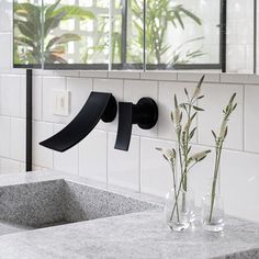 a bathroom sink sitting under a mirror next to a vase with flowers