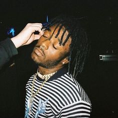 a man with dreadlocks is getting his hair done by another person in the dark