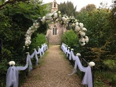 an outdoor wedding ceremony with white flowers and blue ribbon draped over the aisle, surrounded by greenery