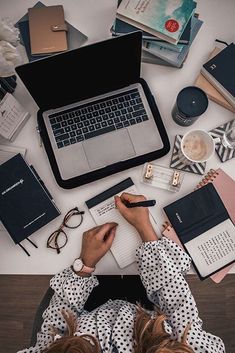 a person sitting at a desk with their laptop and notebooks on top of it