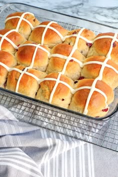 hot cross buns in a glass baking dish on a cooling rack