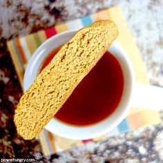 a biscuit is sitting on top of a cup of tea, next to a striped napkin