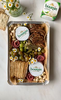 an assortment of food in a tray with crackers, grapes, nuts and cheese