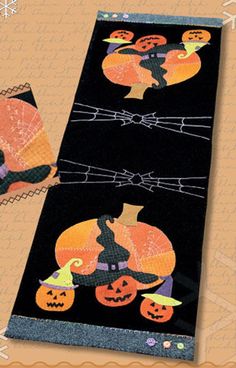 a black table runner with pumpkins on it and a cat hanging from the top