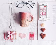 a book, heart shaped candies and glasses are on the table next to a coffee cup