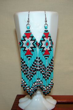 American Indian Motif Earrings, Beaded with 11/0 Round Toho seed beads, these earrings reflect tribal earrings worn by American Indians. They are 4 1/2" from the top of the ear wire, and 1" wide. The earwires are stainless steel 21 gage. The Colors are turquoise, red, black, white. Turquoise Beaded Southwestern Earrings, Southwestern Green Earrings With Dangling Beads, Southwestern Blue Beaded Earrings With Round Beads, Traditional Turquoise Beaded Earrings, Southwestern Green Beaded Dangling Earrings, Southwestern Style Blue Beaded Earrings, Southwestern Round Beads Earrings For Beach, Southwestern Turquoise Earrings With Colorful Beads, Turquoise Large Beads Drop Earrings