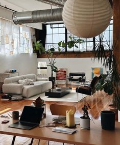 a living room filled with lots of furniture and plants on top of a wooden table