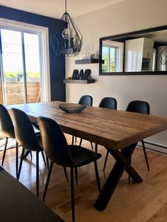 a wooden table with black chairs in front of a window