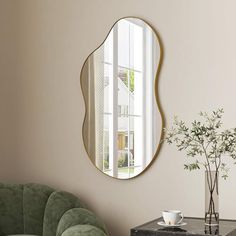 a living room with a round mirror on the wall and a green couch in front of it