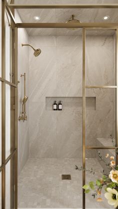 a bathroom with a walk in shower next to a vase filled with flowers and candles