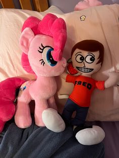 two stuffed animals sitting next to each other on a bed