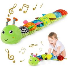 a baby crawling on the ground next to a stuffed caterpillar and musical notes