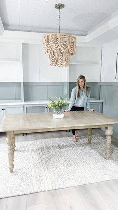 a woman sitting at a wooden table in a room with blue walls and white floors