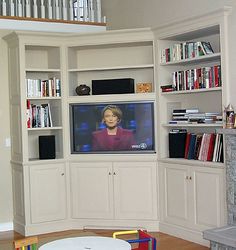 there is a television that is on in the living room with many bookshelves