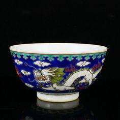 a blue and white bowl sitting on top of a black table next to a wall