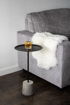 a grey couch with a black table next to it and a white rug on the floor