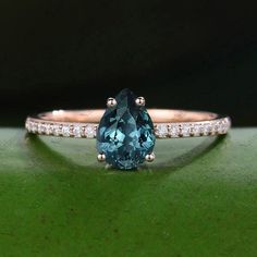 a blue diamond ring with diamonds around it on a green surface, in front of a black background