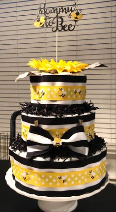 a three tiered cake decorated with yellow and black ribbons