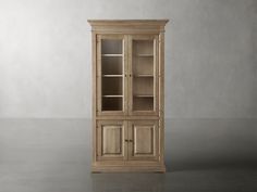 a tall wooden cabinet sitting on top of a gray floor next to a white wall