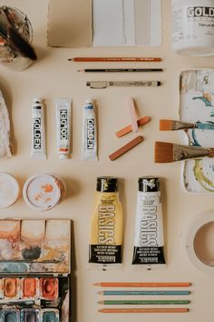 art supplies laid out on a table with paint, pencils, and other items