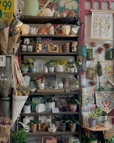 a room filled with lots of plants and potted plants next to shelves full of greeting cards