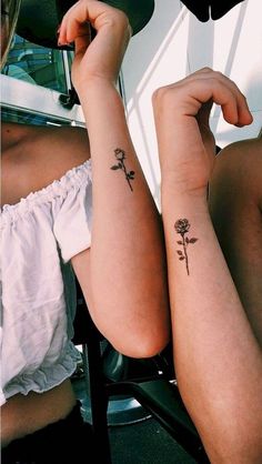 two women with tattoos on their arms sitting next to each other and one has a flower tattoo on her arm