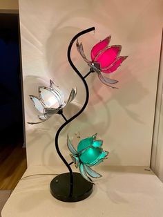 two glass flowers are on display in a room with white walls and wood flooring